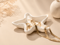 White star-shaped ceramic jewelry tray with gold rings and necklaces